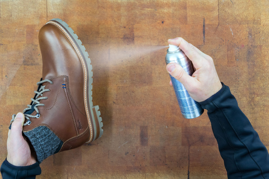 Brauner Sioux Lederschuh wird auf einer Holzfläche gleichmäßig mit Imprägnierspray behandelt, um das Leder vor Nässe und Schmutz zu schützen.